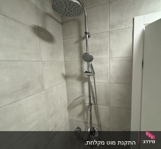ראש מקלחת מותקן על קיר אריחים בחדר אמבטיה